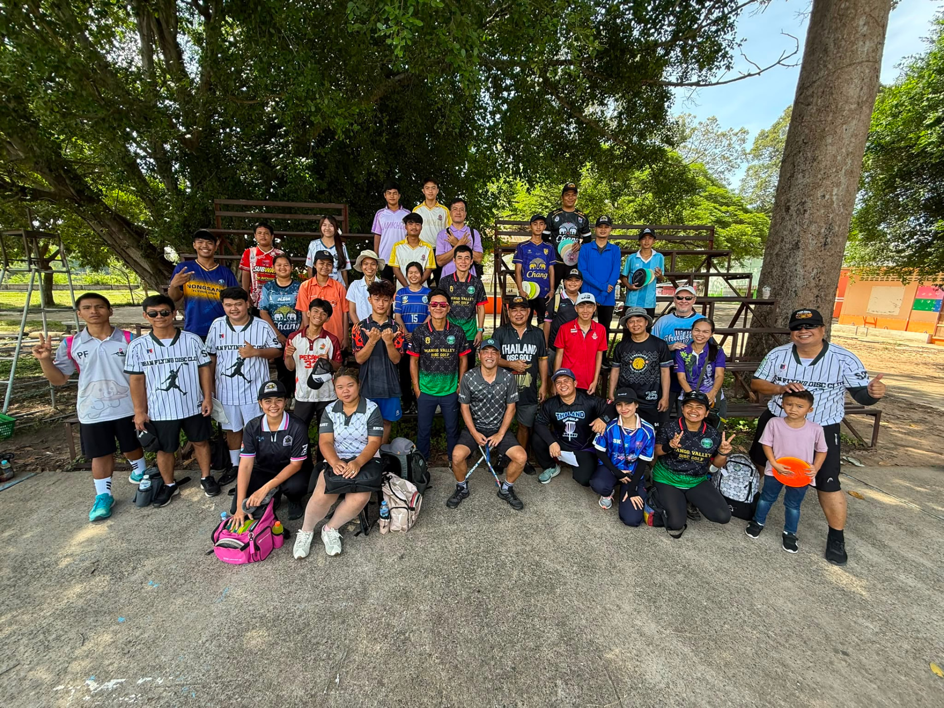 A large group of Thai youth and club disc golf players posing together after an event
